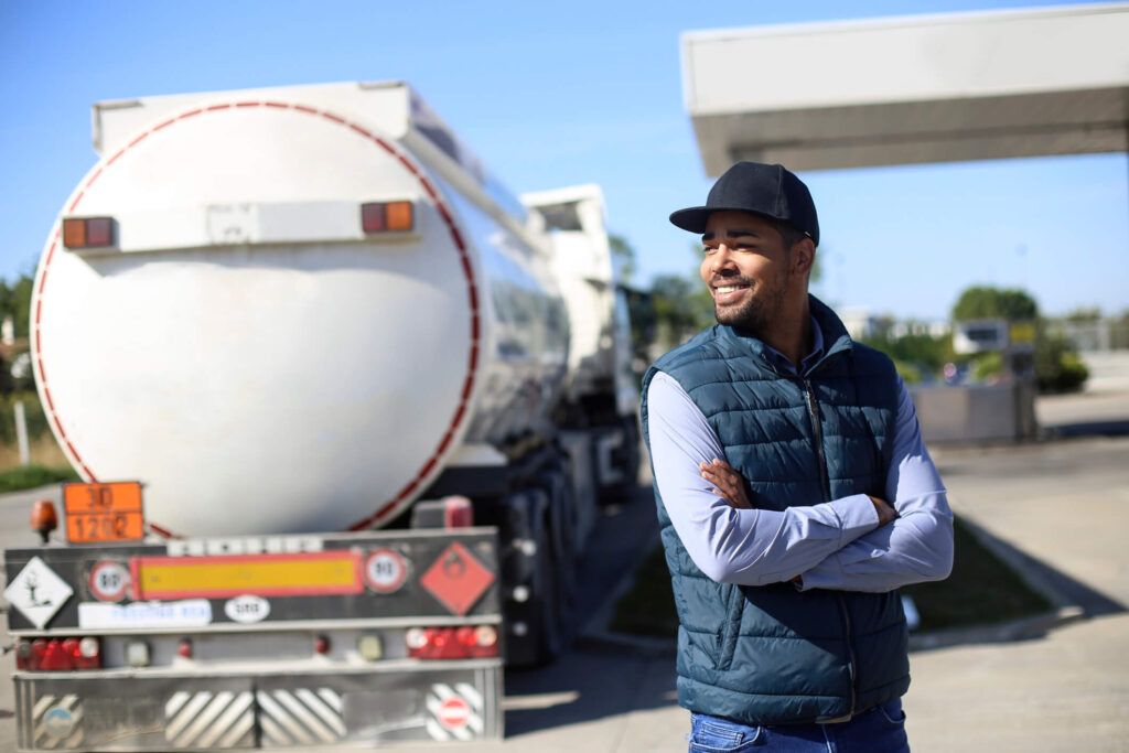 A trucker stands outside his fleet vehicle after using fuel card to gas up.
