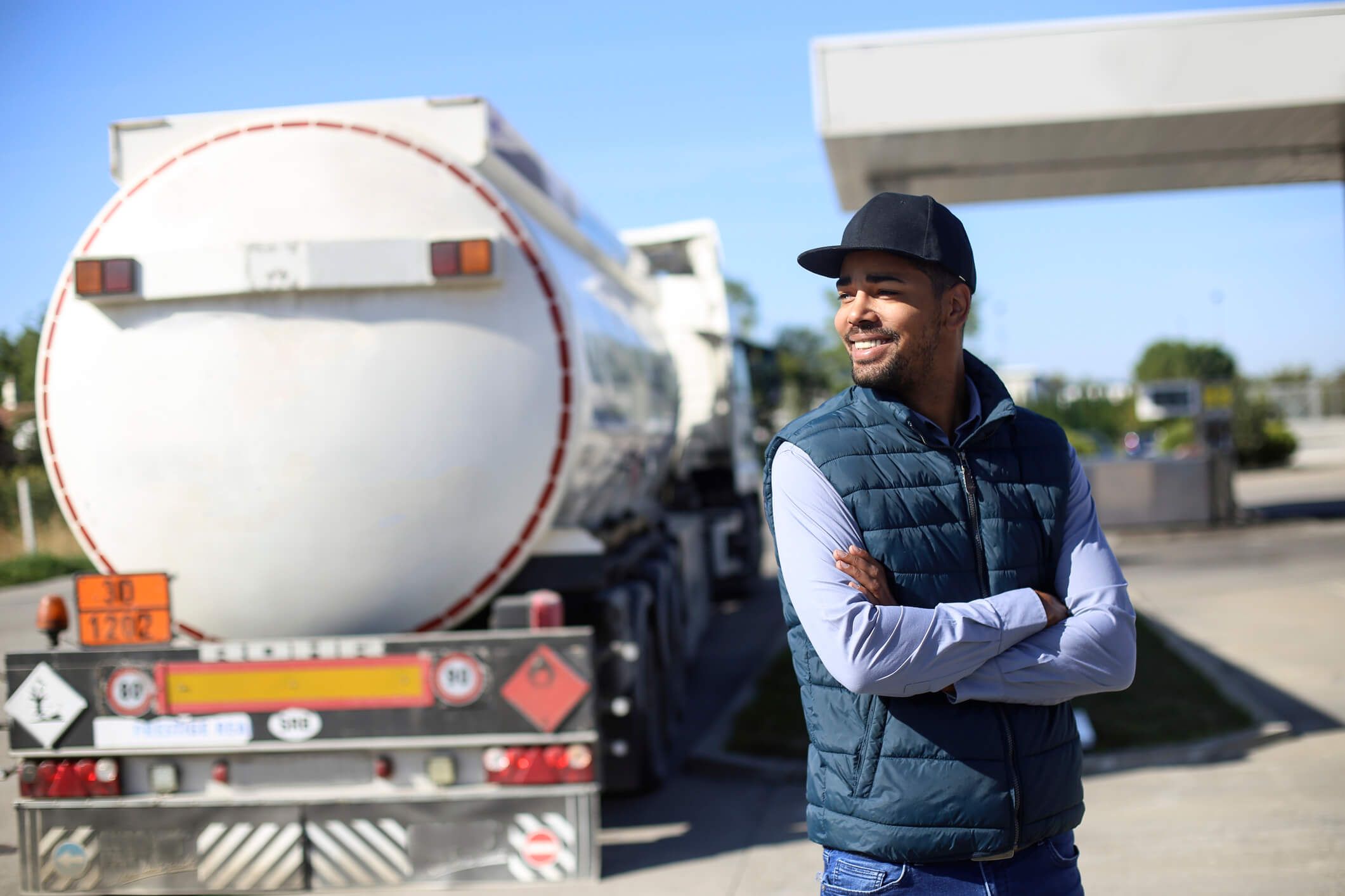 A trucker stands outside his fleet vehicle after using fuel card to gas up.