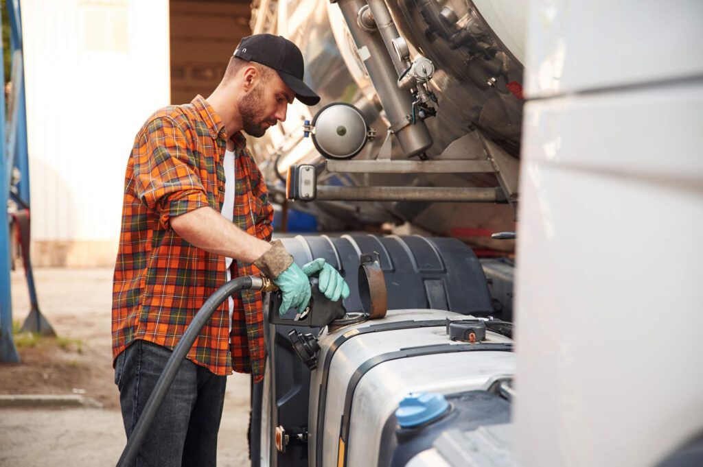 A semi truck driver fills his tank with fuel using a fleet card.