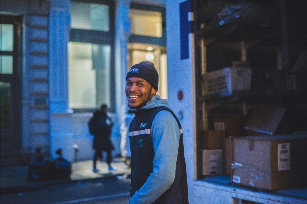 A happy driver of a fleet unloads boxes at his delivery destination.