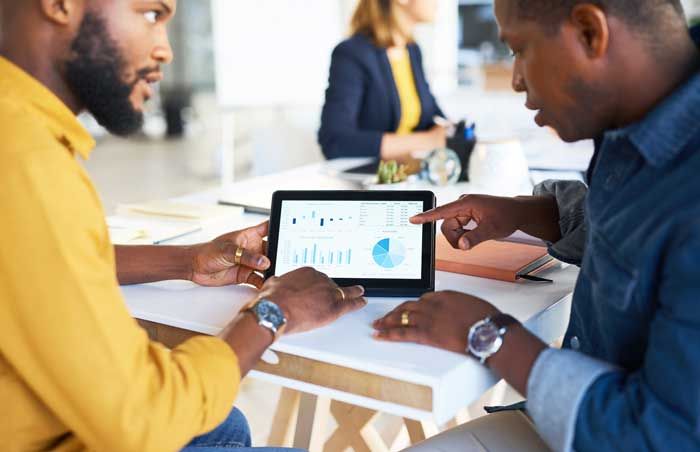 A business owner shares data from fleet fuel cards with a co-worker showing analytics on a tablet.