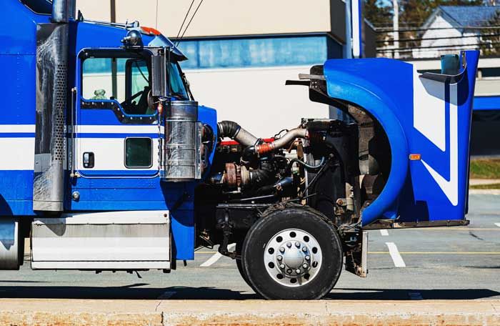 A semi truck hood is open at a maintenance garage for repair work before getting on the road.
