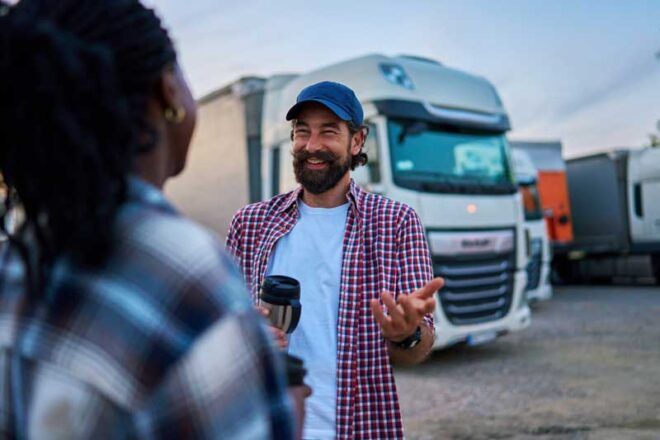 A truck driver and his fellow fleet driver connect outside their trucks.